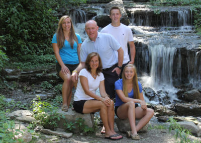 A family pose for a portrait in front of a waterfall.
